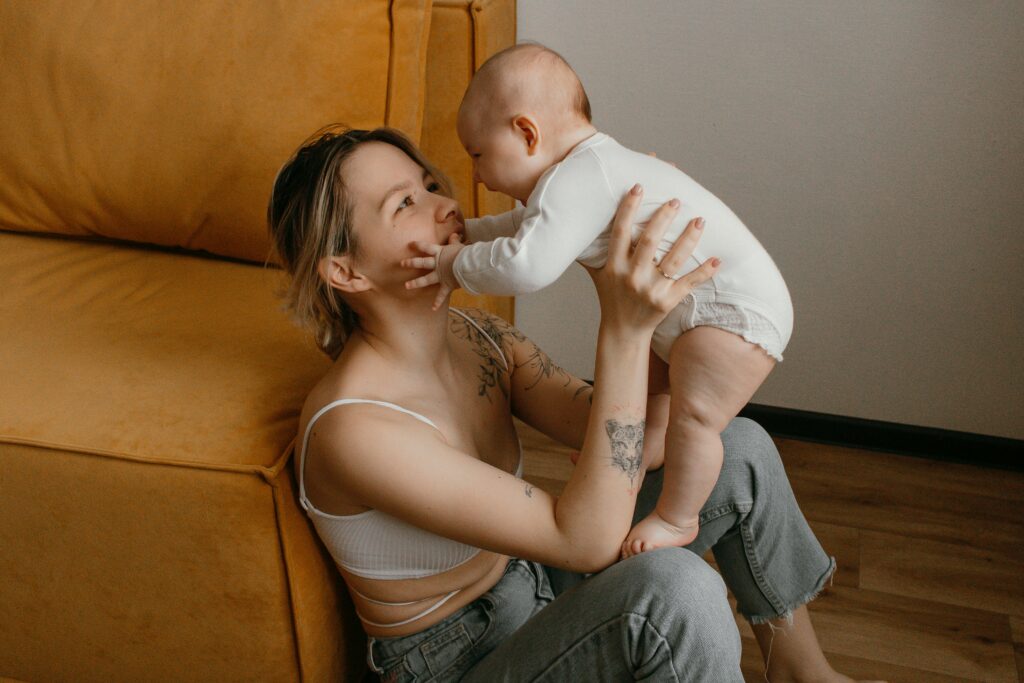 A joyful mother bonding with her baby in a warm, cozy living room setting.
