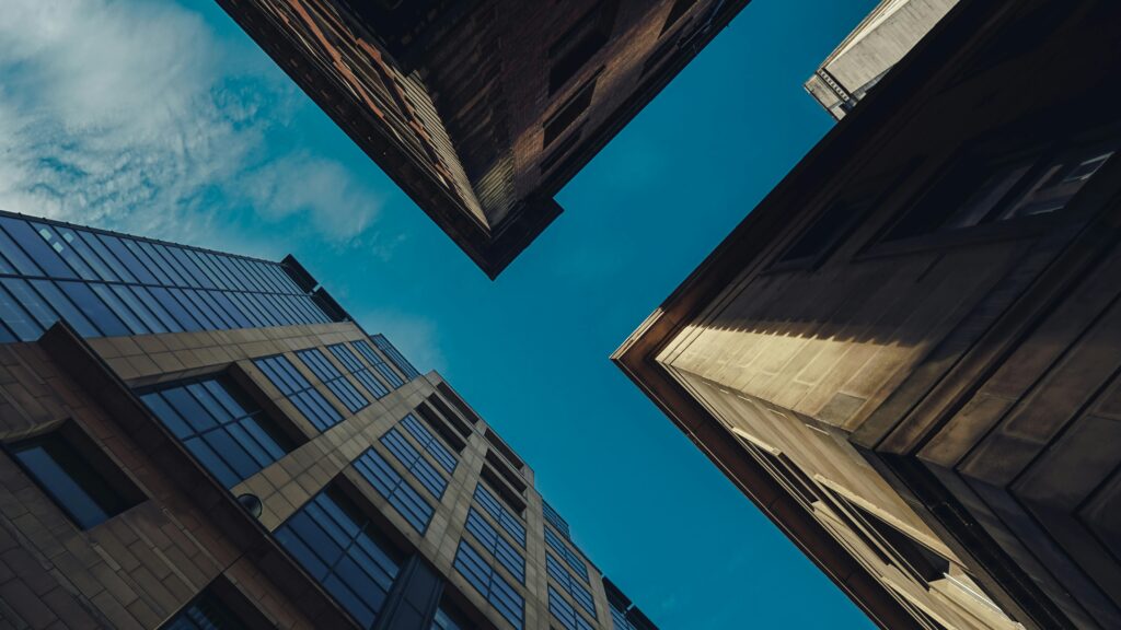 Low-angle view of modern buildings against a clear blue sky in Manchester, UK.